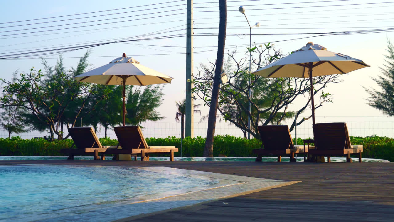 바다를 배경으로 수영장 주변에 침대 수영장이 있는 우산 - 휴일 및 휴가 개념