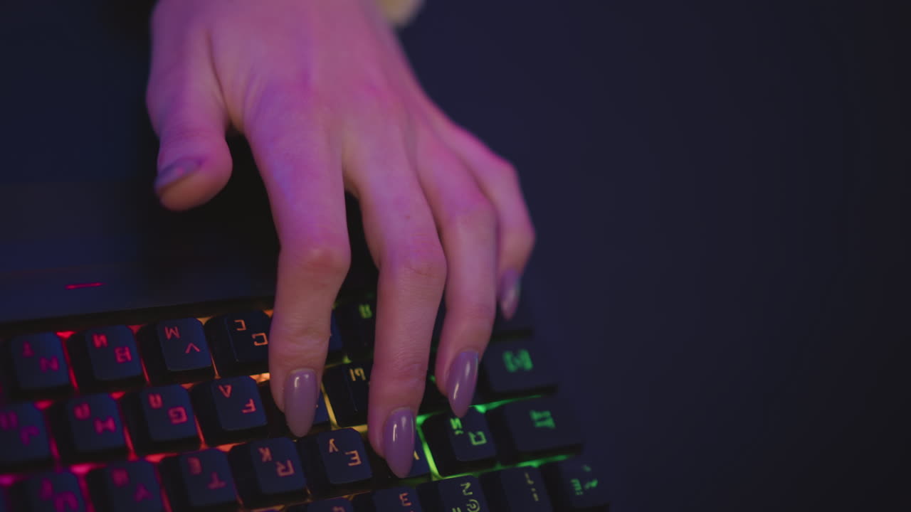top down view of girl hand in fluffy sweater typing on vibrant backlit keyboard with long polished nails under soft colorful lighting during night session in gaming or tech environment