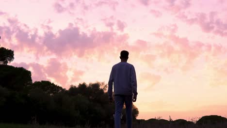 man from behind advancing in a shot at sunset with a beautiful orange sky