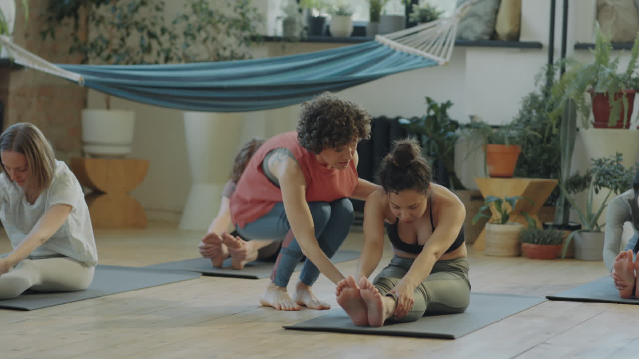 Yoga Instructor Helping Women during Group Practice
