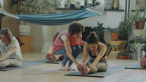 yoga instructor helping women during group practice