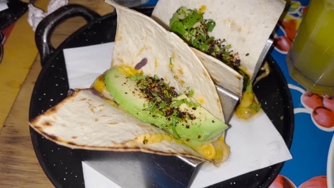 Close-up of freshly made tacos filled with avocado and garnished with herbs and spices, delicious food