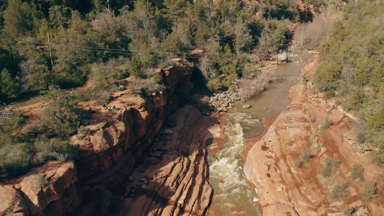 Fly through of desert canyon stream with hikers. 4k footage