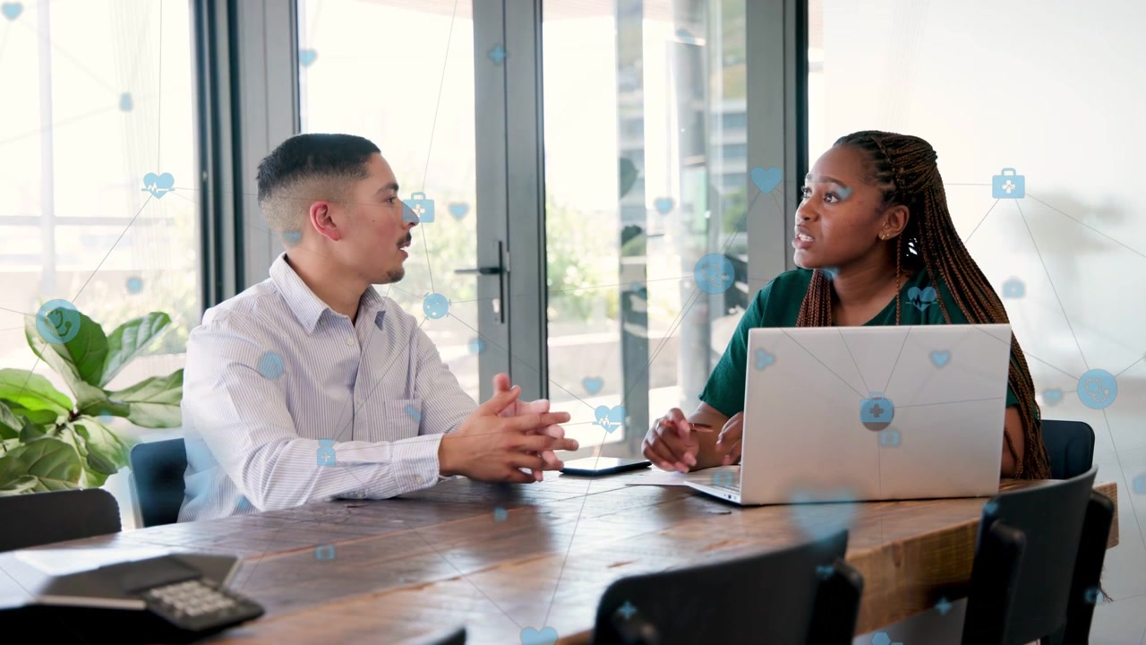 Man leaning forward speaking, woman flipping paper tapping laptop, collaborating on business goals
