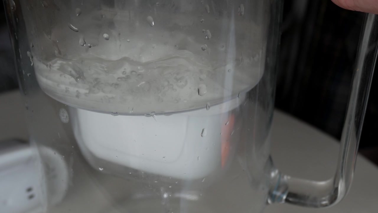 Water filtering jug filled. Water is filtered by carbon filter cartridge as is drips below.