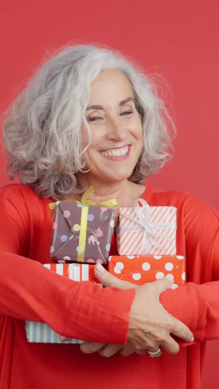 Happy Senior Woman Holding a Stack of Gifts