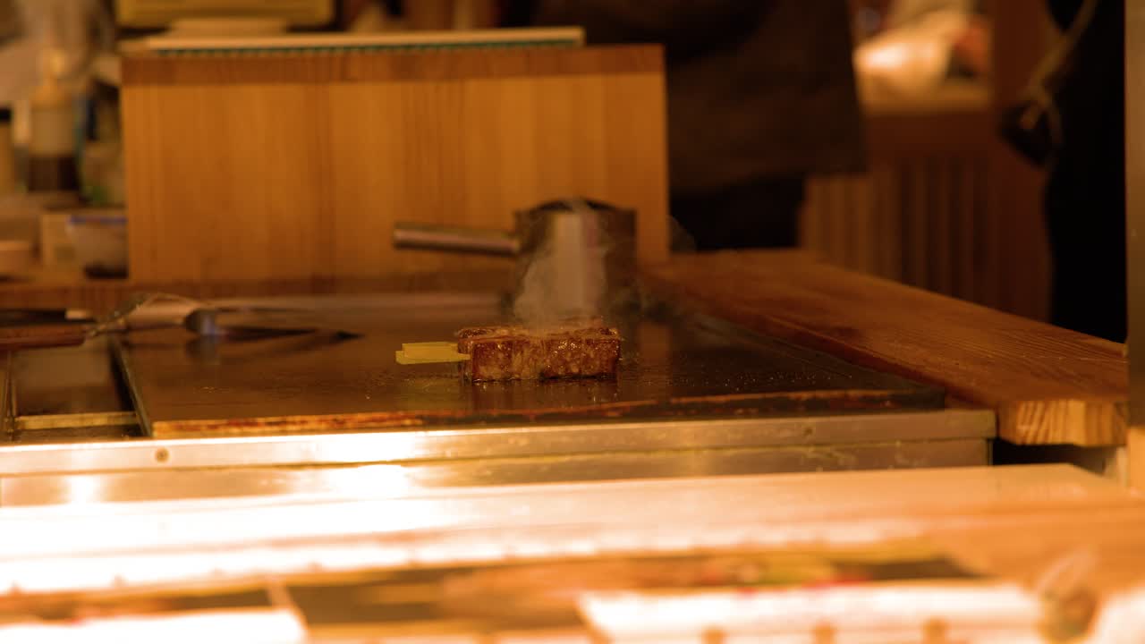 Ein dickes Stück hochwertiges Wagyu-Rindfleisch brutzelt auf einem professionellen Teppanyaki-Grill in Tokio.