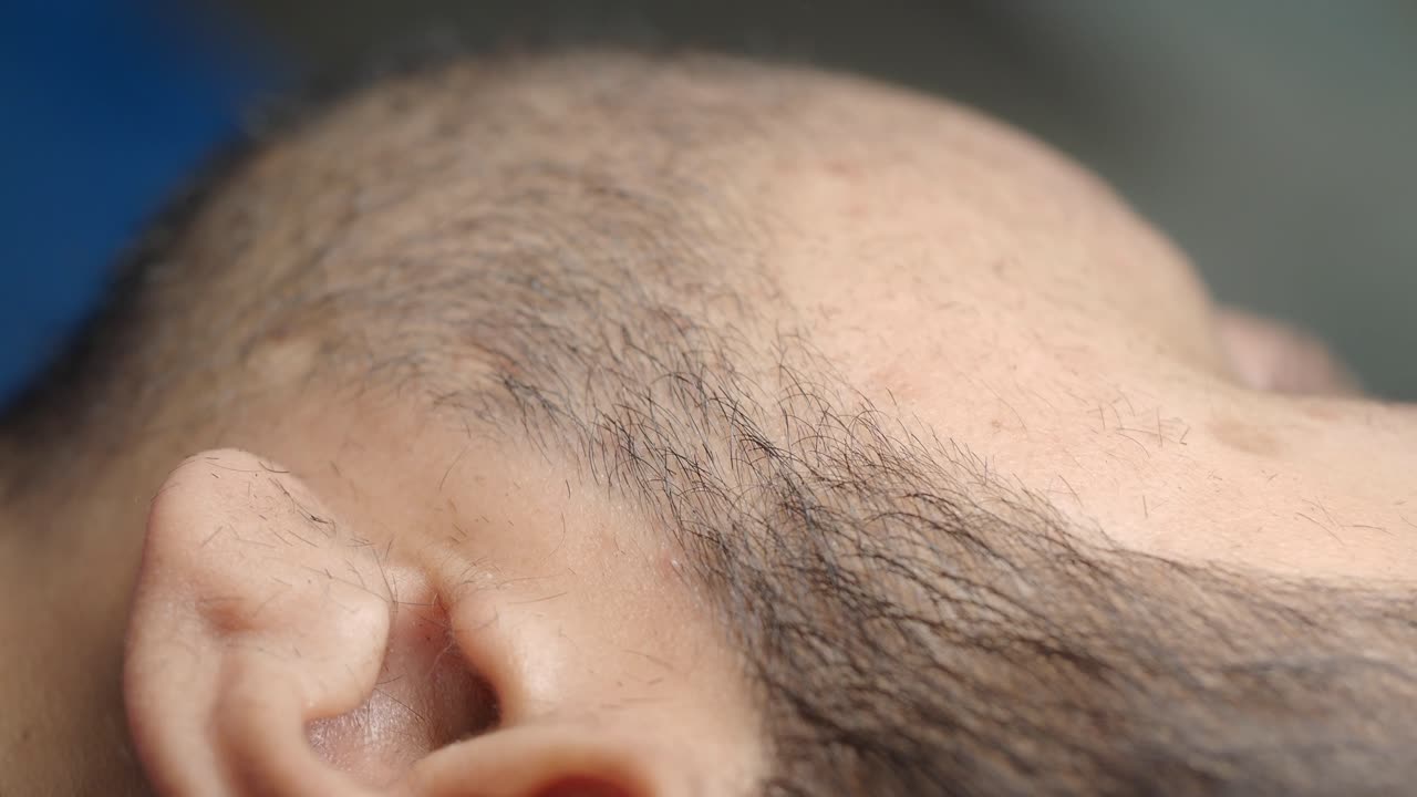 Close-up of a person getting a buzz cut with an electric shaver and comb