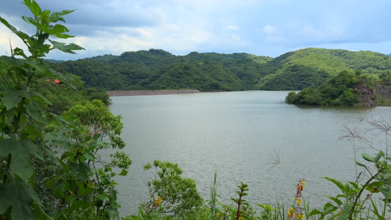 Mountain lake surrounded by lush green hills and vegetation at Presa El Carrizo in Tamazula de Gordiano, Jalisco, Mexico