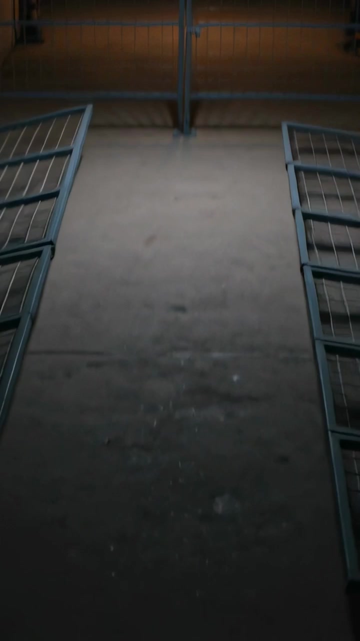 Vertikal video: Løftende kamera, trappeskakt og metalgelænder afslører slidt gulv, varmt lys.