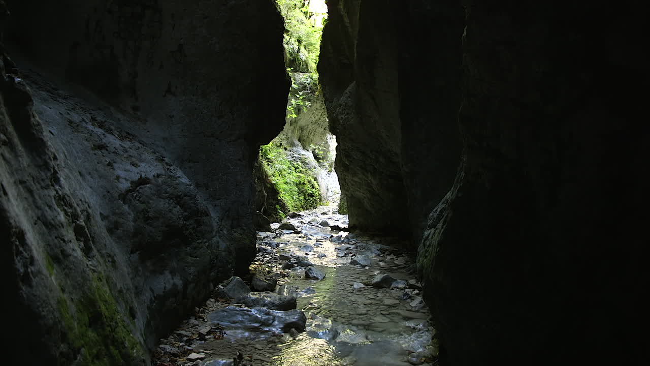 Lush green vegetation at the end of a deep narrow canyon with a stream of crystal clear cold water