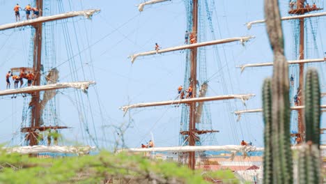 marineros trabajando en las sábanas del mástil, velas y aparejos mientras el barco está amarrado en el puerto de curazao