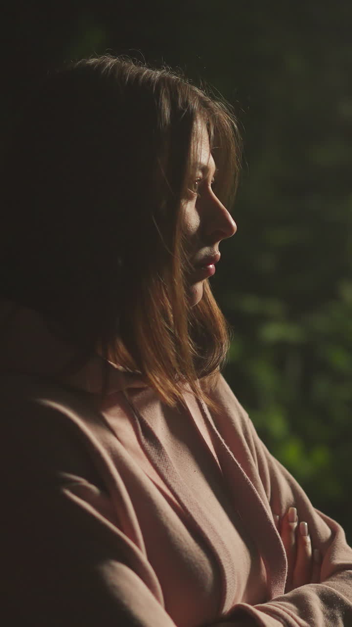 joven pensativa respira fuertemente en el aire fresco del bosque mientras está de pie bajo la luz de la lámpara de la calle. persona femenina solitaria en abrigo cálido se siente triste mientras se relaja en la naturaleza