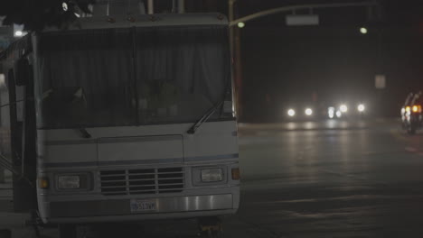 a static shot of a white bus standing on a vacant road at night