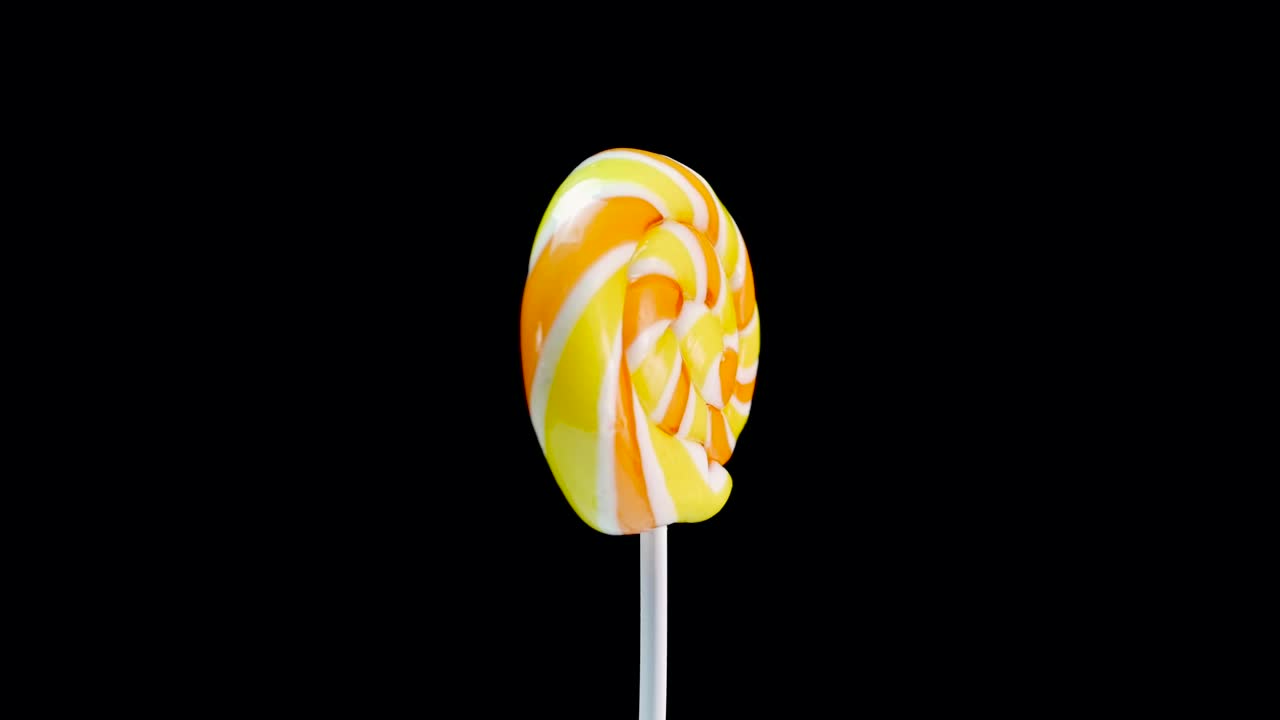 вращающийся фруктовый спиральный леденчик на черном фоне. карамельный леденник. сладости для детей.