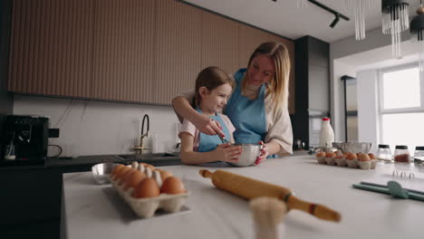 una niña feliz y su mamá están cocinando juntas la madre está enseñando a su hija a cocinar la familia pasa el tiempo en casa