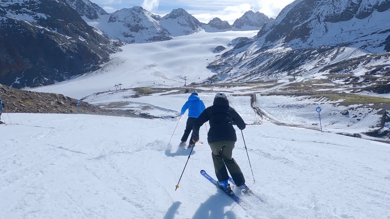 Sci alpino su ghiacciaio di giovani sciatori e sciatrici con una splendida dimostrazione e una buona tecnica. Maestro di sci professionista che esegue curve strette con una vista mozzafiato e alte montagne innevate
