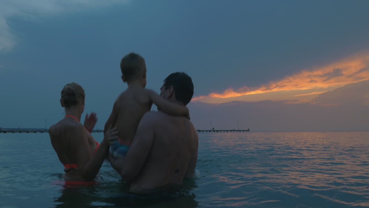 어린 가족 이 저녁 에 바다 목욕 을 즐기고 있다