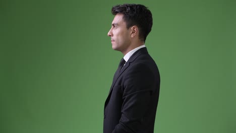 young handsome hispanic businessman against green background