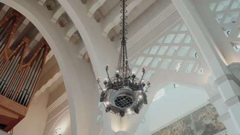 ornate chandelier hanging from the ceiling of a cathedral with visible organ pipes in the background