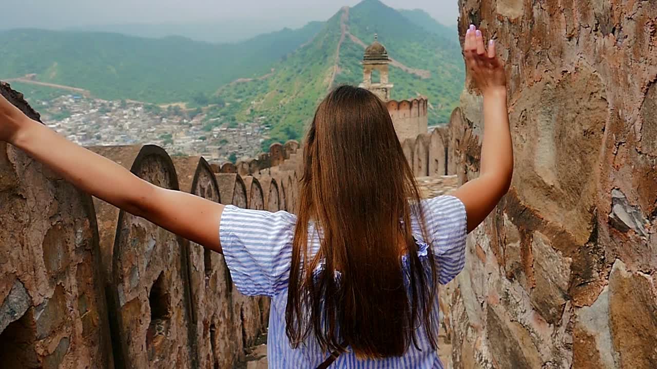 Slow motion (120fps): happy young female enjoys exploring the fort in Jaipur (India) and runs cheerfully