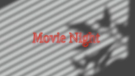 red serif movie night text glowing on blurred striped background, casting soft plant leaf shadows