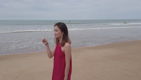 Young-asian-woman-wear-red-dress-and-walking-relaxing-on-the-beach-at-summer-vacation-holidays-in-slowmotion