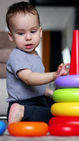 lovely caucasian toddler builds a toy pyramid. happy child growing and developing. vertical video