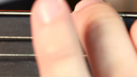 macro shot of guitarist fingers pressing old and rusty acoustic guitar strings