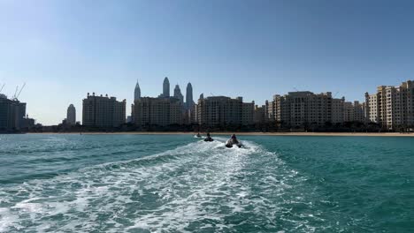 tourists riding on speedboats across the persian gulf with view of dubai cityscape in background