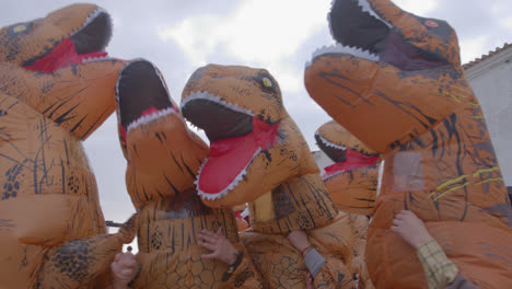 dinosaur costume wearing woman dance in the street in the town of nazare, portugal