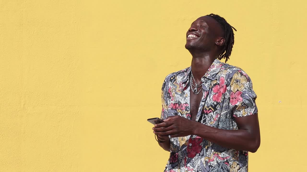 Uomo nero elegante con una camicia colorata e uno smartphone