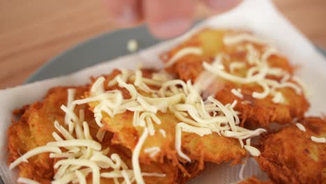 primer plano de un delicioso plato de aperitivos de hojaldre de patata mientras se espolvorea queso encima