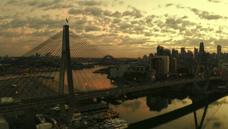 Drone-aerial-view-of-traffic-flowing-over-a-suspended-bridge-across-a-river