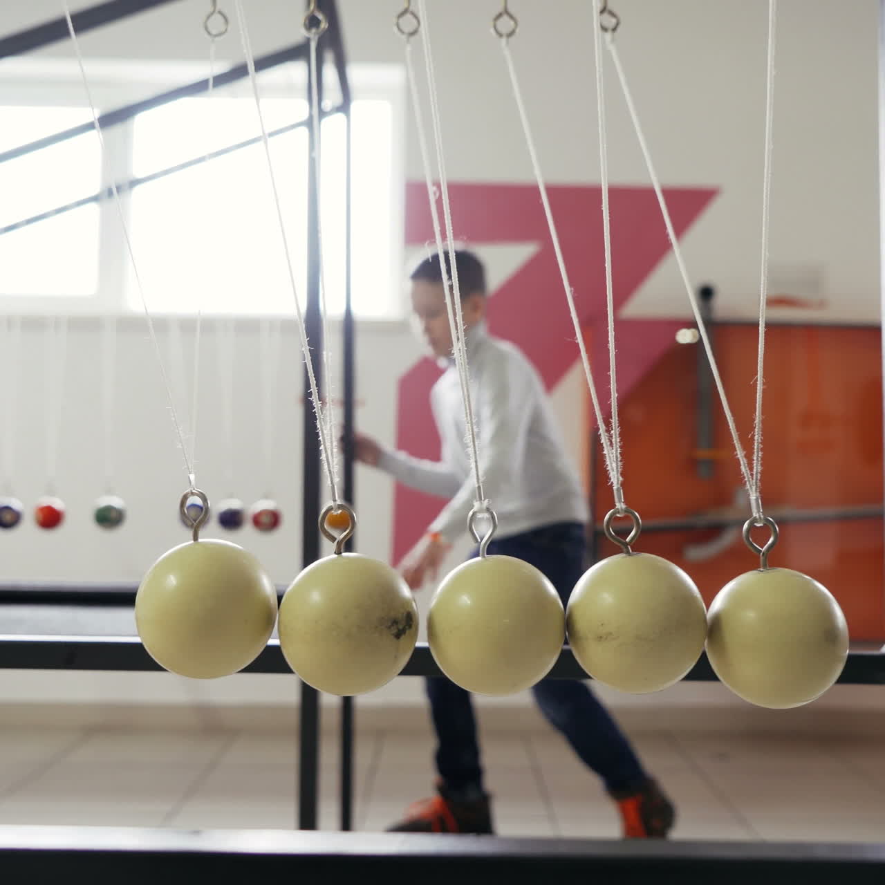 Boy makes an experiment with Newton's pendulum. The concept of physics. Museum of Science Square video