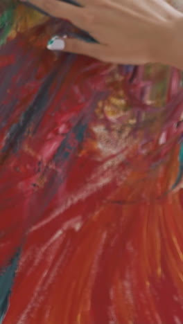 skilled young woman artist with palm in grey paint at work on impressive abstract painting on easel in studio slow motion extreme close view