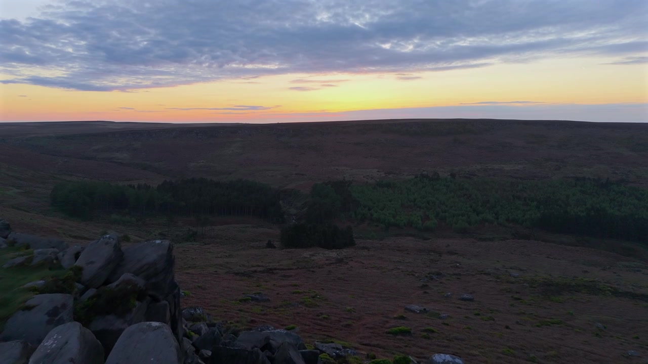 A low drone flight over Higger Tor towards the Burbage Valley at sunrise.