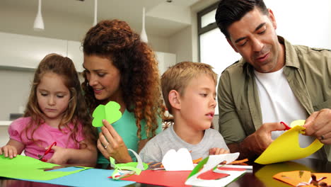 padres y niños felices haciendo artes y artesanías en la mesa de la cocina