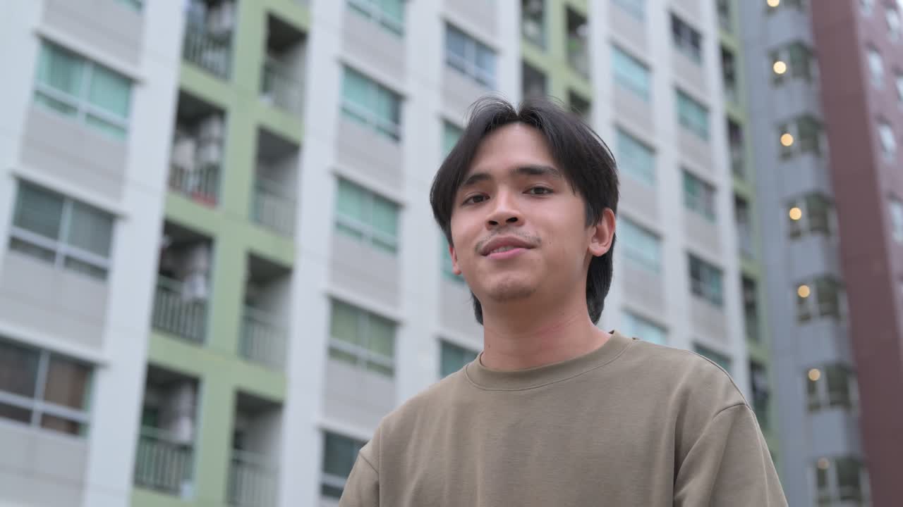 Handsome young Asian Thai man in early 20s talking and smiling while looking at camera
