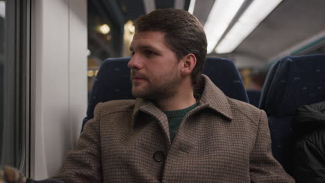 young caucasian business man in an overcoat sitting on a train - closeup