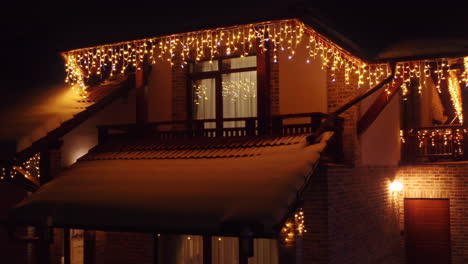 aerial drone tracking shot of house covered with beautiful christmas lights