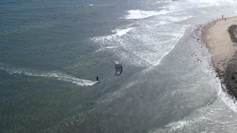 skilled windsurfer along the coast of california on a windy day - aerial follow view