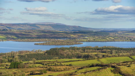 timelapse of rural nature farmland with hills, mixed forests and lake in distance during sunny cloudy spring day viewed from carrowkeel in county sligo in ireland