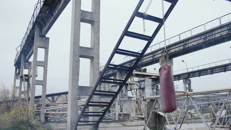 abandoned industrial factory ruins with a red punching bag hanging in the middle on a cloudy morning