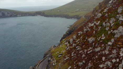Vehicles-passing-each-other-on-narrow-road-winding-along-steep-slope-high-above-sea-coast.-Amazing-panoramic-route-around-Slea-Head.-Ireland