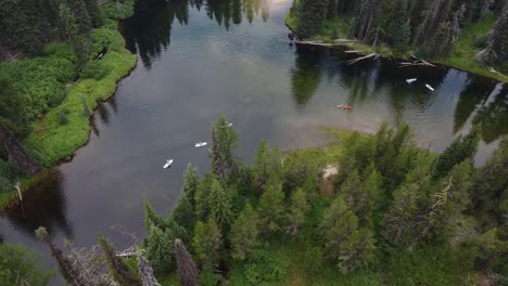 counterclockwise drone shot of paddleboarders and kayakers coming around a bend in the payette river in the idaho wilderness