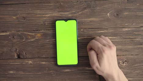 male hands with a smartphone with a chroma key on the table. view from above