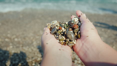 female hands hold a handful of wet pebbles rest on the sea meditation concept 4k video