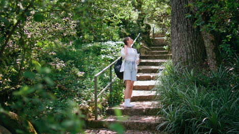 girl going downstairs forest trail with backpack contemplating nature beauty.