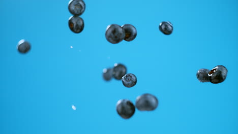 blueberries splashing in water against a vibrant blue background